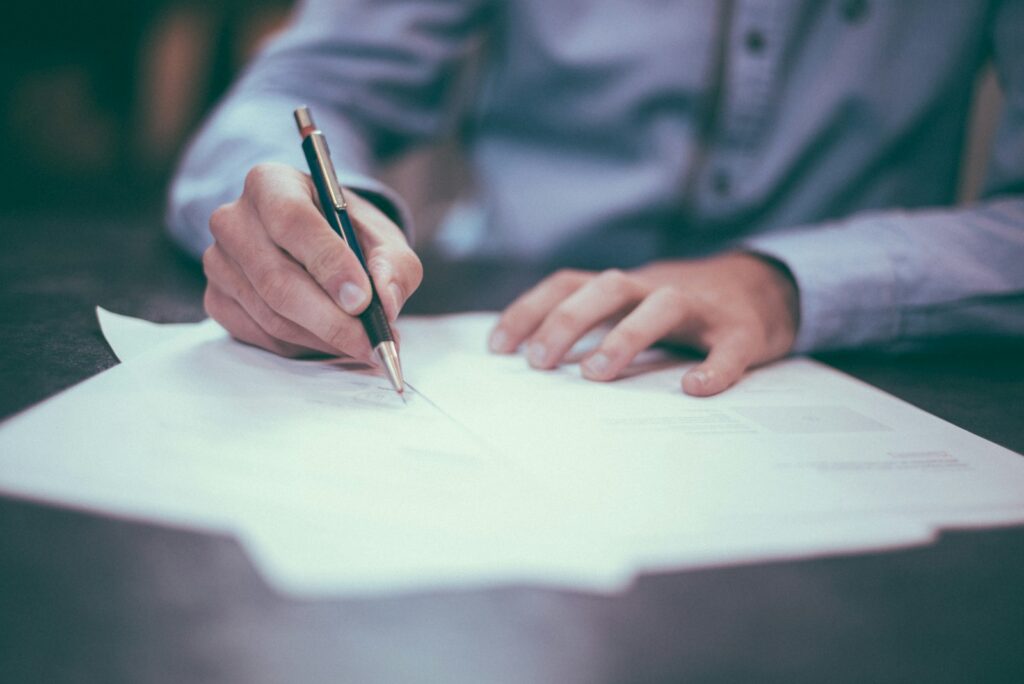 Person signing a real estate contract with a pen